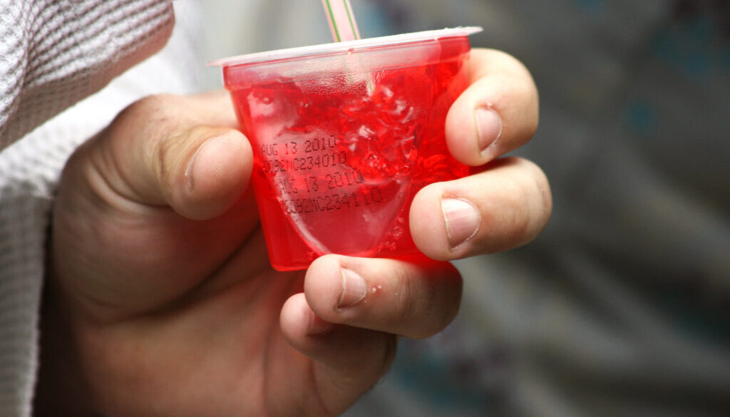 Person eating a cup of red jell-o.