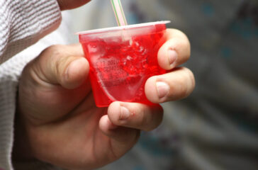 Person eating a cup of red jell-o.