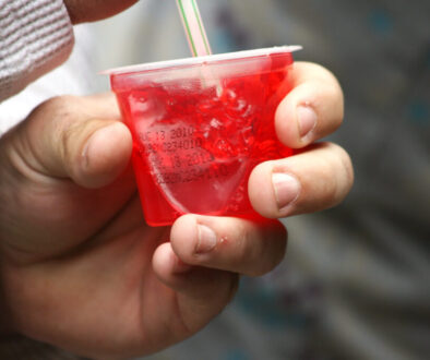 Person eating a cup of red jell-o.